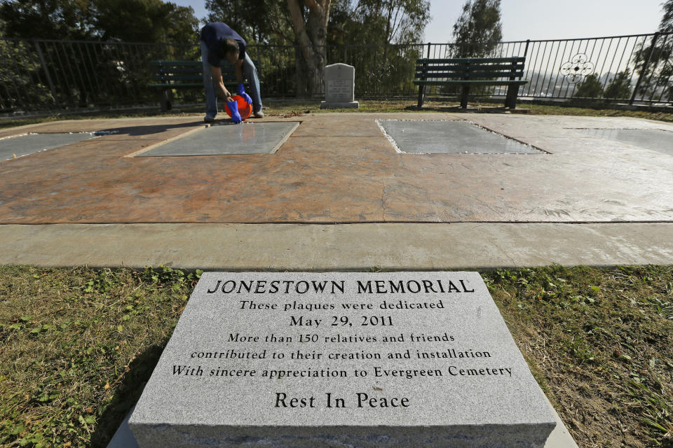 In this Thursday, Oct. 25, 2018, photo, former Peoples Temple member Jim Jones Jr. places bleached rocks around the edges of the Jonestown victim memorial in the Evergreen Cemetery in Oakland, Calif. Ceremonies were held at the cemetery to mark the mass murders and suicides 40 years earlier of more than 900 Americans orchestrated by the Rev. Jim Jones at a jungle settlement in Guyana, South America. The unclaimed or unidentified remains of more than 400 victims of the Jonestown tragedy on Nov. 18, 1978, are buried at the cemetery. (AP Photo/Eric Risberg)