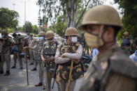 Indian policemen stand guard as Indian farmers block a highway during a protest in Noida on the outskirts of New Delhi, India, Friday, Sept. 25, 2020. Hundreds of Indian farmers took to the streets on Friday protesting new laws that the government says will boost growth in the farming sector through private investments, but they fear these are likely to be exploited by private players for buying their crops cheaply. (AP Photo/Altaf Qadri)