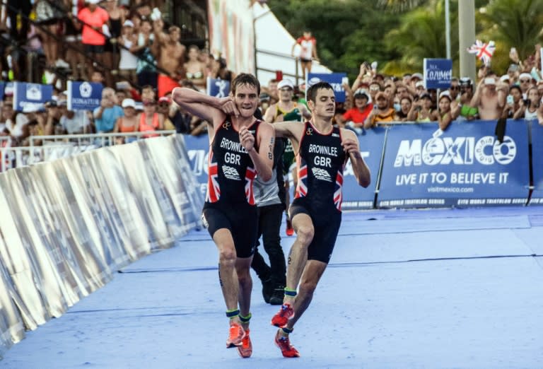 British athlete Alistair Brownlee (L) helps his brother Jonathan Brownlee (R) before crossing the line in second and third place during the ITU World Triathlon Championships 2016 in Cozumel, Quintana Roo, Mexico on September 18, 2016