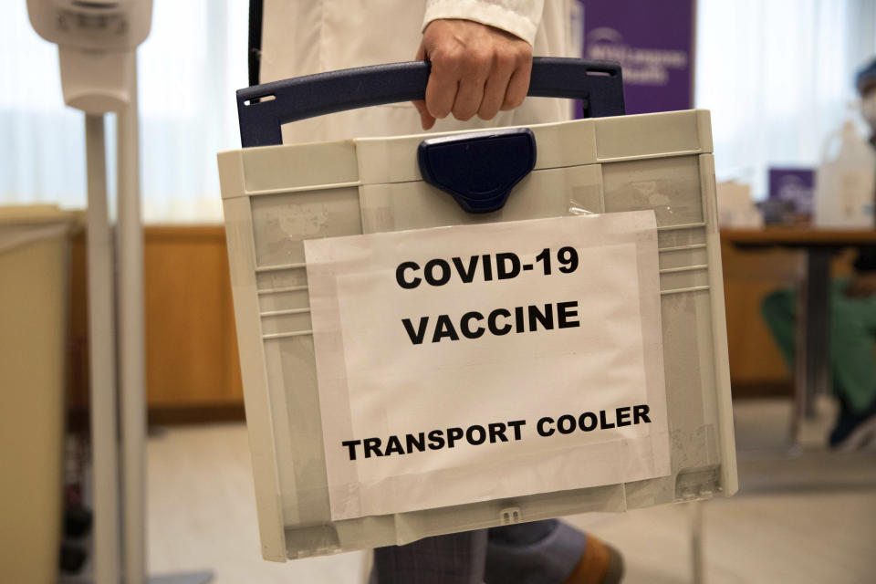 A pharmacist arrives with a cooled box containing the COVID-19 vaccine at NYU-Langone Hospital on Monday, Dec. 14, 2020, in New York. Hundreds of thousands of health care workers are expected to receive the vaccine this week. (AP Photo/Kevin Hagen).