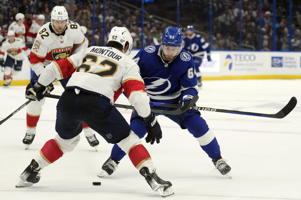 Tampa Bay Lightning center Tyler Motte (64) tries to get past Florida Panthers defenseman Brandon Montour (62) and center Kevin Stenlund (82) during the second period of an NHL hockey game Wednesday, Dec. 27, 2023, in Tampa, Fla. (AP Photo/Chris O'Meara)