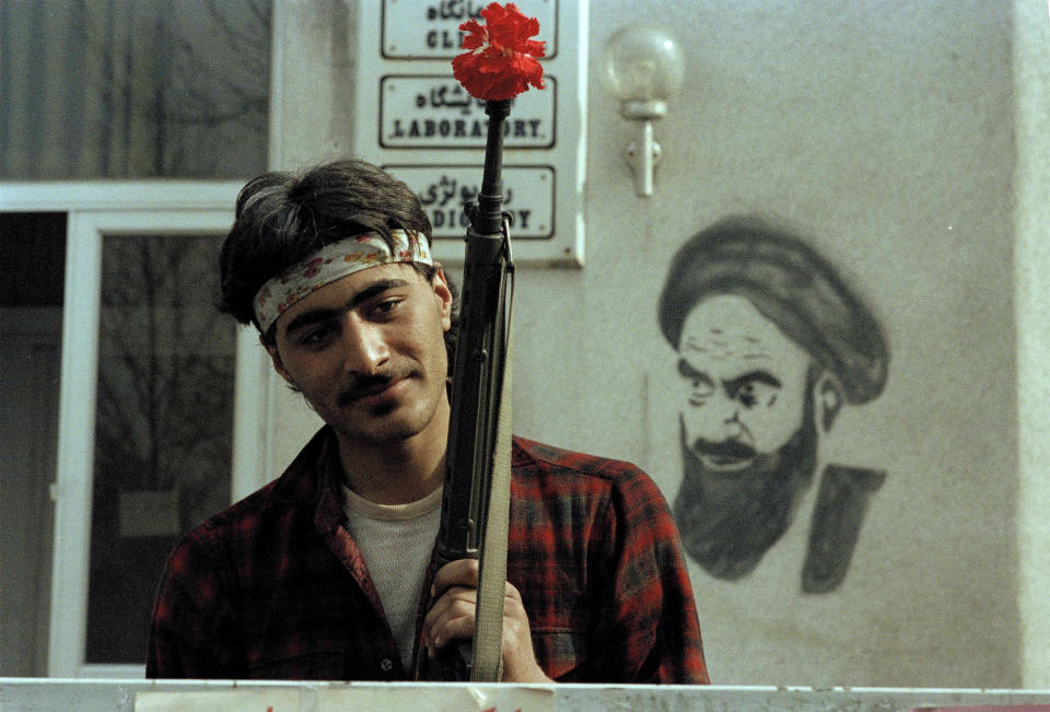 FILE - In this Feb. 15, 1979 file photo, a follower of Ayatollah Ruhollah Khomeini holds a rifle containing a flower outside of Khomeini's headquarters in Tehran, Iran. The demonstrations that erupted after Iran admitted to accidentally shooting down a Ukrainian jetliner early Wednesday, Jan. 8, 2020, during a tense standoff with the United States, are the latest of several waves of protest going back to the 1979 Islamic Revolution — all of which have been violently suppressed. (AP Photo/Michel Lipchitz, File)