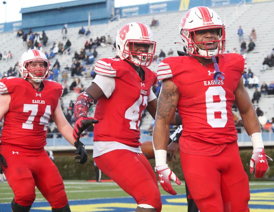 Smyrna's Yamir Knight (8) celebrates his score with Nathan Roscoe (74) and Julian Charlescar in the second quarter against Dover in the DIAA Class 3A championship at Delaware Stadium, Saturday, Dec 10, 2022.