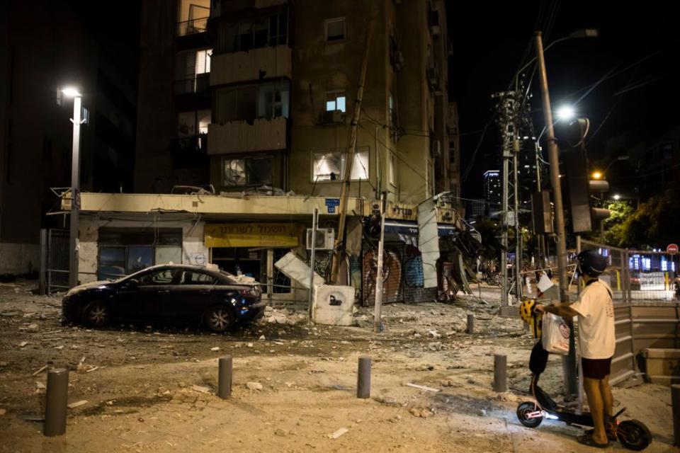 A man passes the scene where a rocket fired from the Gaza Strip hit a building in Tel Aviv.