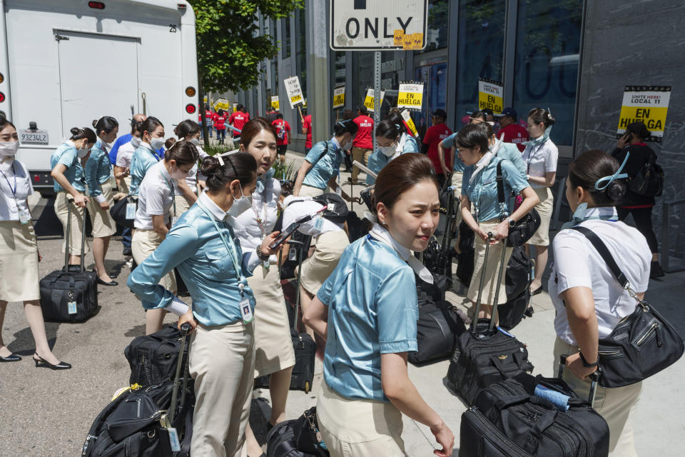 Korean Air airlines flight attendants are dropped off their bus on the street sidewalk of the InterContinental Los Angeles Downtown as striking hotel workers rally outside Monday, July 3, 2023, in downtown Los Angeles. (AP Photo/Damian Dovarganes)