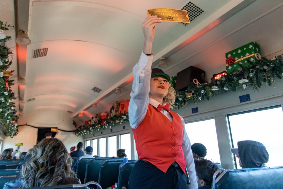 Crew members hold up golden tickets on "The Polar Express Train Ride" in 2022 at the Oklahoma Railway Museum.