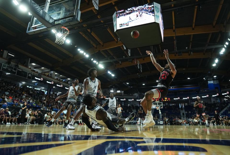 Calgary Surge's Sean 'Rugzy' Miller-Moore, right, shoots over a falling Scarborough Shooting Stars' Myck Kabongo, front left, during the first half of the CEBL basketball championship final, in Langley, B.C.