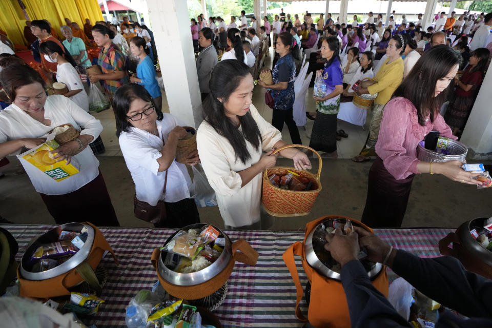 Relatives of the victims offer the food into monk bowl during the Buddhist ceremony in the rural town of Uthai Sawan, in Nong Bua Lamphu province, northeastern Thailand, Friday, Oct. 6, 2023. A memorial service takes place to remember those who were killed in a grisly gun and knife attack at a childcare center. A former police officer killed 36 children and teachers in the deadliest rampage in Thailand's history one year ago. (AP Photo/Sakchai Lalit)