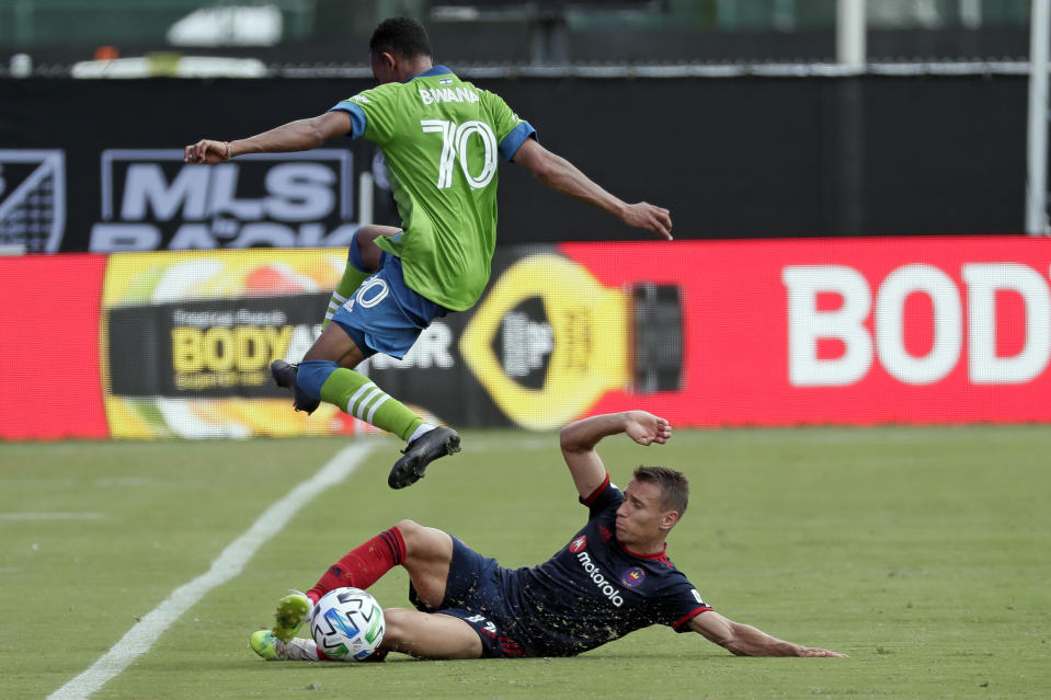 Handwalla Bwana (70) de los Sounders de Seattle salta sobre Przemyslaw Frankowski del Fire de Chicago en el partido de la MLS en Kissimme, Florida, el martes 14 de julio de 2020. (AP Foto/John Raoux)