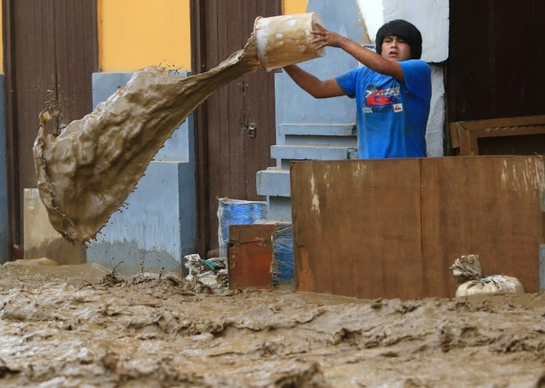 A local resident bails water from behind a barrier as a flash flood hits the city of Trujillo, 570 kilometres north of Lima on March 18, 2017