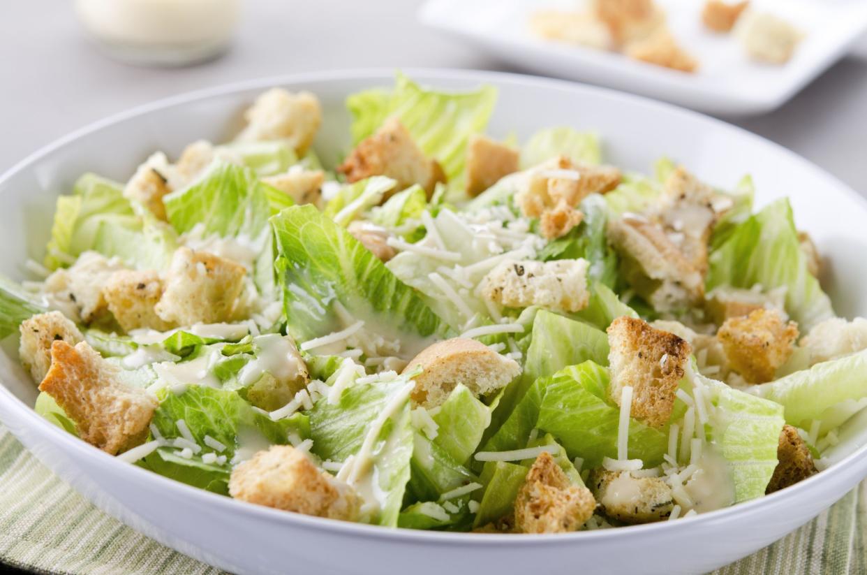 SEVERAL MORE IN THIS SERIES. Closeup of a fresh caesar salad, with romaine lettuce hearts, croutons, parmesan cheese and dressing.  Dressing and croutons in background.  Very shallow DOF.