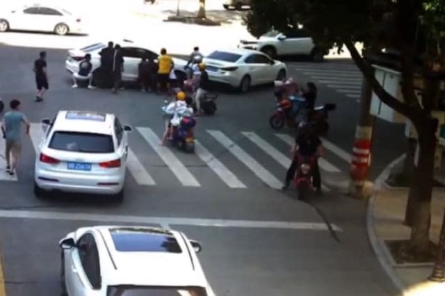 Passersby lift car up together to free biker trapped under the vehicle in China