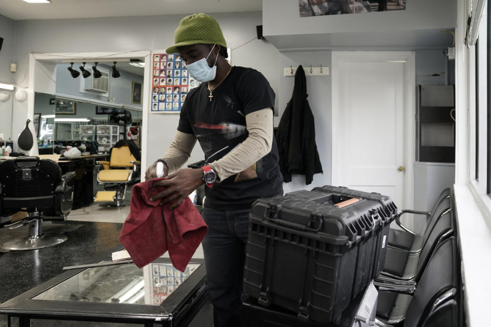 A worker at the popular Top Class Barber Shop in Falls Church, Va., a suburb of Washington, cleans surfaces in preparation for a possible reopening after weeks of forced closure during the COVID-19 pandemic, Monday, May 11, 2020. The Northern Virginia suburbs of Washington are a significant part of the state's economy, but the region's top elected officials are objecting to Gov. Ralph Northam's plan to begin lifting shutdown restrictions there because of the lingering coronavirus health emergency. (AP Photo/J. Scott Applewhite)