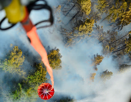 An Oregon Army National Guard Chinook helicopter dumps a 2,000 gallon capacity Bambi Bucket amid smoke over the Mt. Jefferson Wilderness area in order to support firefighting efforts on the Whitewater Fire in Oregon, U.S. on August 5, 2017. Courtesy Leslie Reed/Oregon National Guard/Handout via REUTERS