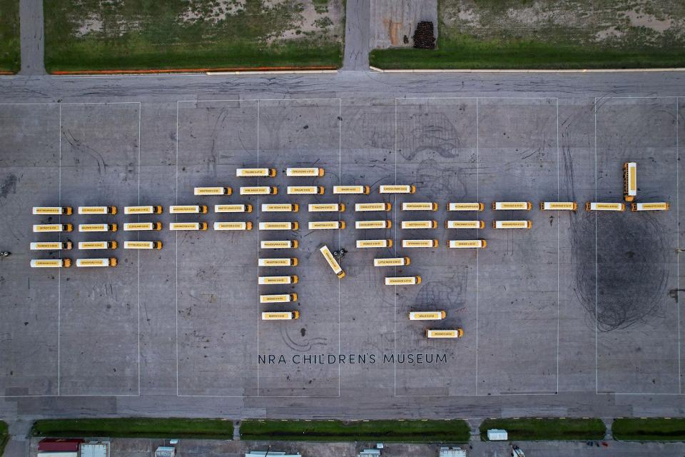 An aerial view of 52 empty school buses, which represent the number of schoolchildren killed by gun violence since 2020, parked to resemble an assault rifle in Houston on July 13, 2022.