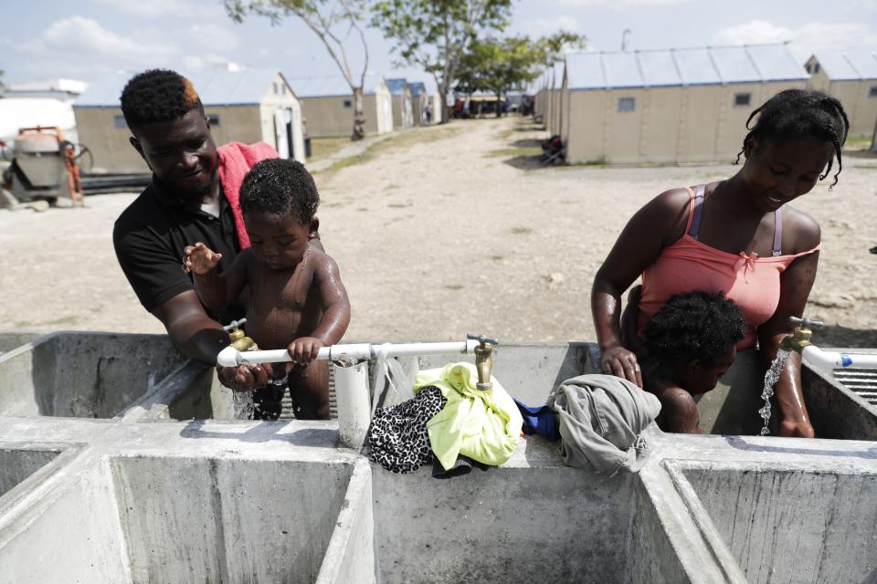 Haitian migrants bathe their children at a migrant camp amid the new coronavirus pandemic in San Vicente, Darien province, Panama, Tuesday, Feb. 9, 2021. Panama is allowing hundreds of migrants stranded because of the pandemic, to move to the border with Costa Rica, after just reopening its land borders. (AP Photo/Arnulfo Franco)