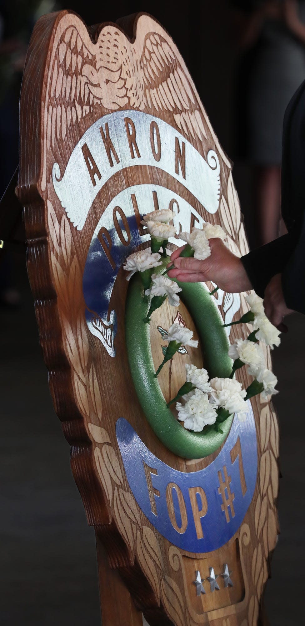 A member of the Fraternal Order of Police auxiliary places a carnation in a wreath during the roll call of fallen officers during the ceremony on Akron Police Memorial Day in Akron.