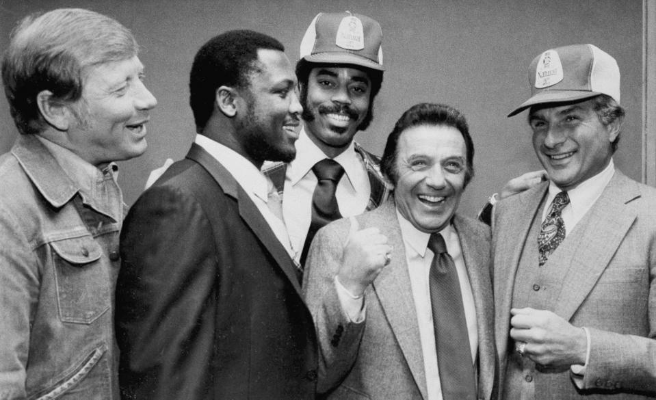 FILE - In this March 1980 file photo, comedian Norm Crosby, second from right, gives a thumbs-up as he is surrounded by sports figures, from left, Mickey Mantle, Joe Frazier, Walt Frazier and Nick Buoniconti in New York, to launch a new ad campaign for a light beer. Crosby, the deadpan mangler of the English language who thrived in the 1960s, ’70s and ’80s as a television, nightclub and casino comedian, has died. He was 93. Crosby’s daughter-in-law, Maggie Crosby, told the New York Times that the comic died Saturday, Nov. 7, 2020 of heart failure in Los Angeles. (AP Photo/Marty Lederhandler, File)