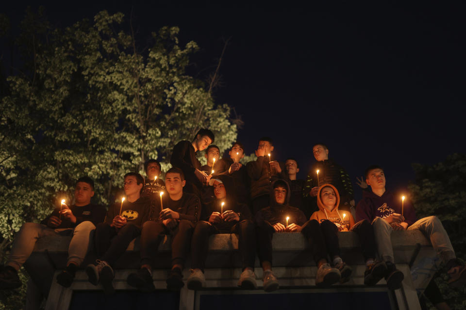 People hold candles for the victims near the Vladislav Ribnikar school in Belgrade, Serbia, Wednesday, May 3, 2023. Police say a 13-year-old who opened fire at his school drew sketches of classrooms and made a list of people he intended to target. He killed eight fellow students and a school guard before being arrested. (AP Photo/Armin Durgut)