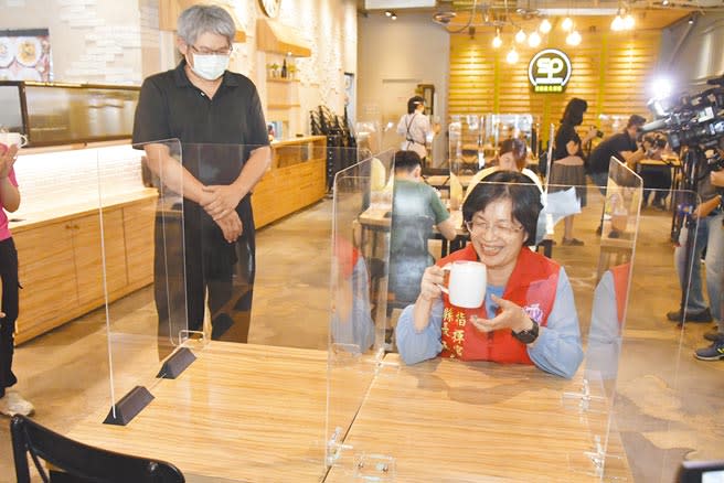 彰化縣長王惠美（右）27日至餐飲場所視察防疫措施，業者林芳信（左）送上咖啡，她坐在隔板內喝了口咖啡，露出難得笑容，直說「這感覺真棒！」。（謝瓊雲攝）