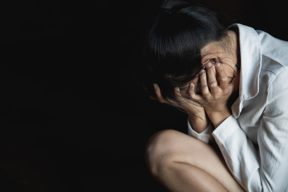 Woman crouched with face covered