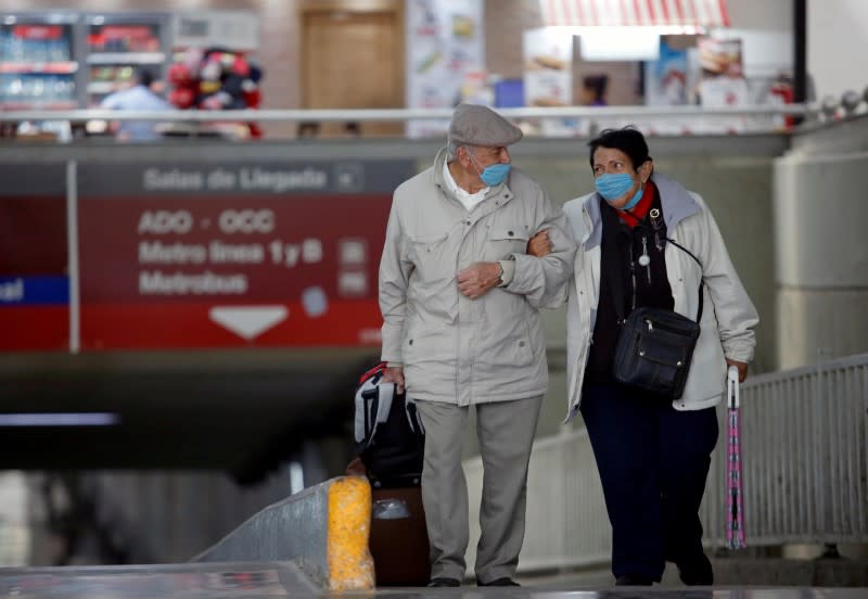 An elderly couple wearing protective masks arrives at the TAPO bus terminal in Mexico City