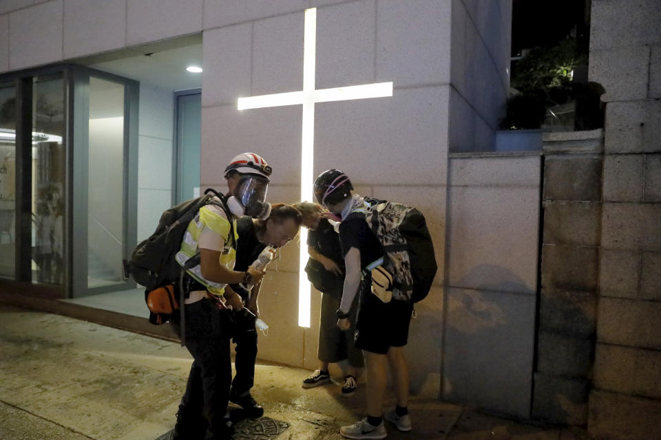 Residents react to tear gas during a confrontation in Hong Kong on Saturday, Aug. 10, 2019. Hong Kong is in its ninth week of demonstrations that began in response to a proposed extradition law but have expanded to include other grievances and demands for more democratic freedoms.(AP Photo/Kin Cheung)