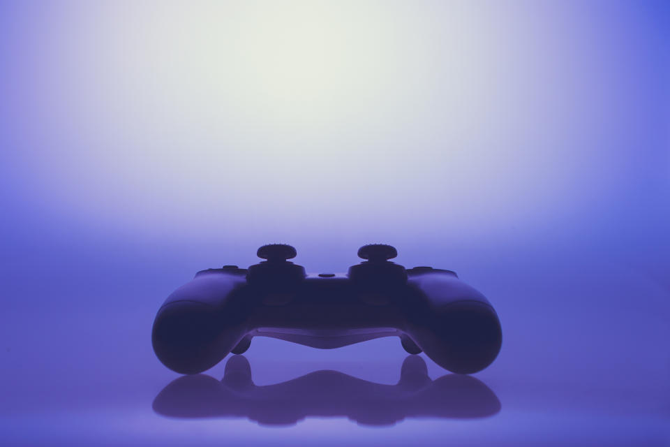 A black video game controller set against a purple background.