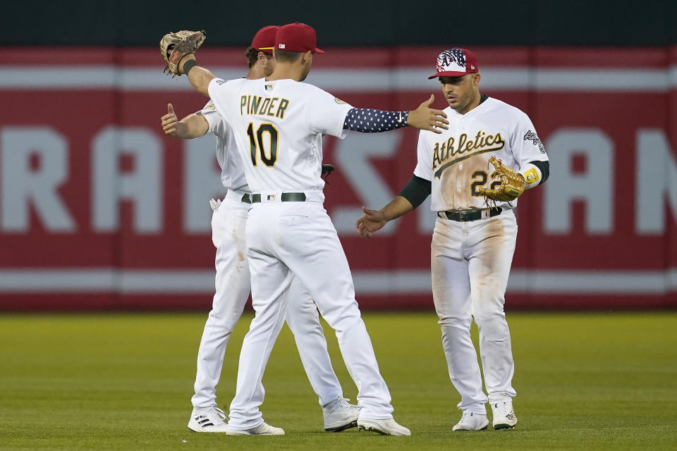 Oakland Athletics' Chad Pinder (10) celebrates with Skye Bolt, obscured, and Ramon Laureano after the Athletics defeated the Toronto Blue Jays in a baseball game in Oakland, Calif., Monday, July 4, 2022. (AP Photo/Jeff Chiu)