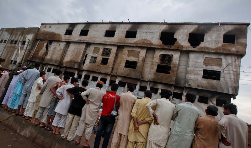 FILE PHOTO: Residents stand outside a garment factory that caught fire the day before, in Karachi