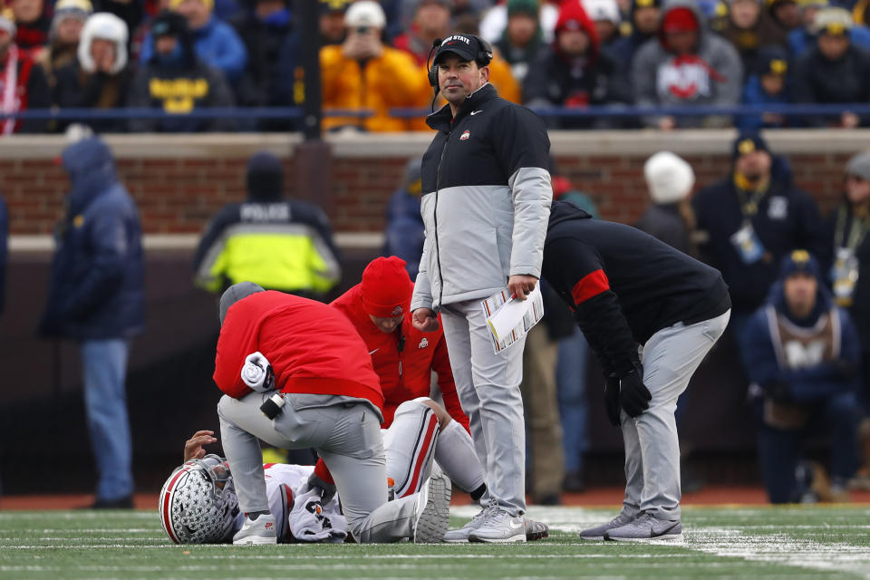 Ohio State head coach Ryan Day looks on as quarterback Justin Fields is helped by medical staff after being injured in the second half of an NCAA college football game against Michigan in Ann Arbor, Mich., Saturday, Nov. 30, 2019. Fields returned to the game with a knee brace. (AP Photo/Paul Sancya)