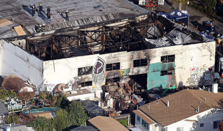 FILE PHOTO: Recovery teams examine the charred remains of the two-story converted warehouse that caught fire killing dozens in Oakland, California, U.S., December 4, 2016. REUTERS/Lucy Nicholson/File Photo