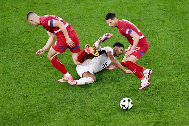 England's Jude Bellingham (C) and Serbia's Nikola Milenkovic (L) and Sasa Lukic battle for the ball during the UEFA EURO 2024 Group C soccer match between Serbia and England at Arena AufSchalke. David Inderlied/dpa