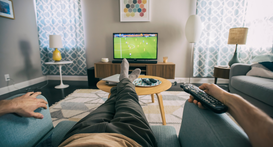 man laying on chair watching soccer on amazon fire tv holding remote, amazon canada tv deal