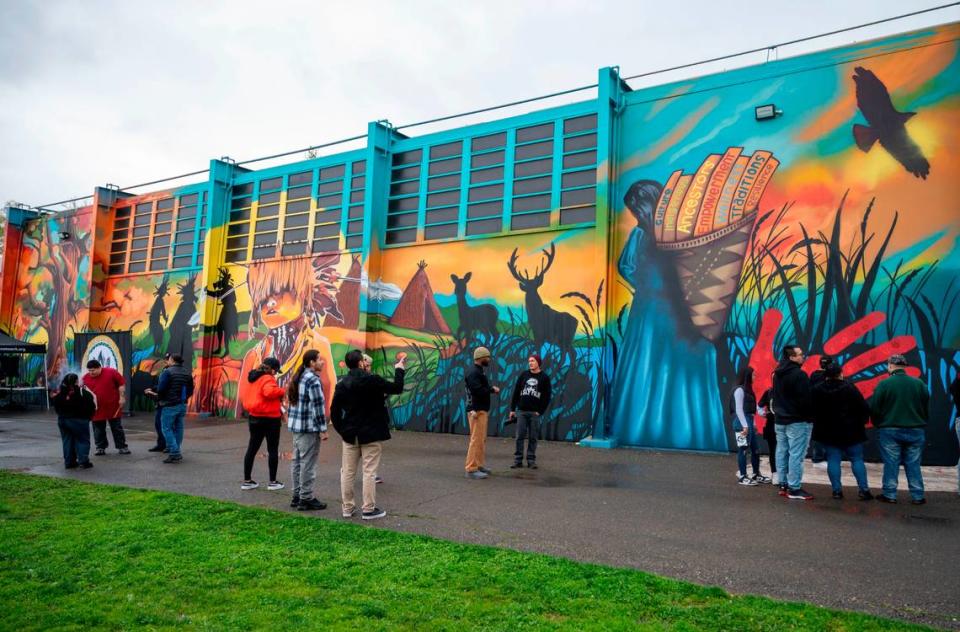 Members of the community look at a 30’ tall and 100’ wide mural during an unveiling ceremony Saturday at Miwok Middle School, formerly Sutter Middle School, depicting scenes and elements of Miwok life. Lezlie Sterling/lsterling@sacbee.com