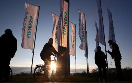 FILE PHOTO: People pass Siemens flags ahead of the company's annual shareholders meeting in Munich, Germany, January 31, 2018. REUTERS/Michael Dalder