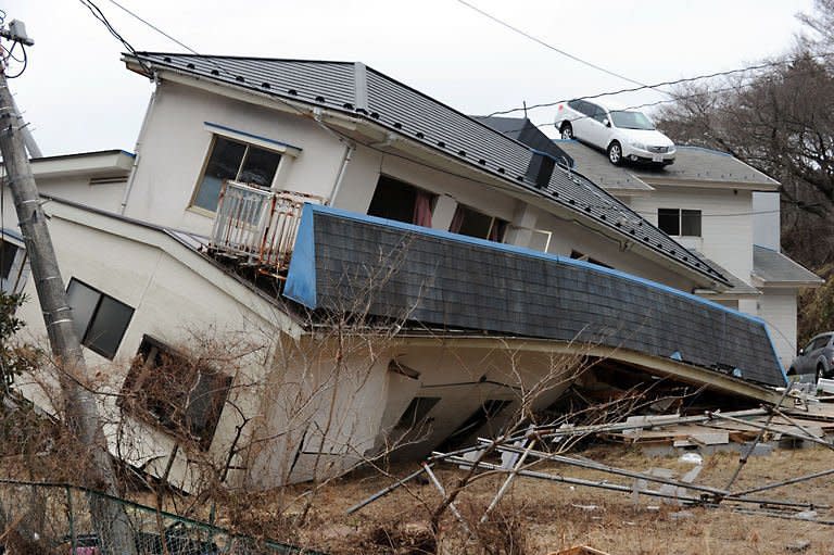 A vehicle is lifted onto the rooftop of a collapsed house by the tsunami is pictured in a small village beside the Onagawa nuclear plant in Onagawa in Miyagi prefecture. Smoke belched from a stricken nuclear plant in Japan on Monday, disrupting urgent efforts to repair the cooling systems as Tokyo halted some food shipments owing to radiation worries