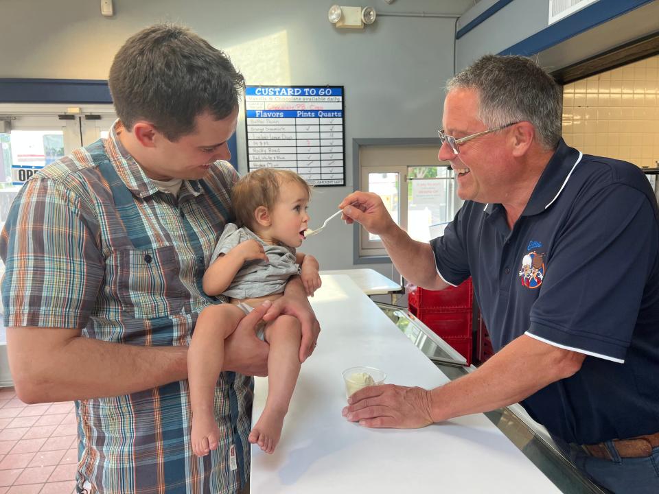 Willy Linscott holds his daughter Avi while his father Tom feeds her custard at Gilles, the frozen custard stand the family owns. The photo was a recreation of one that featured Willy as a baby being fed by his grandfather Robert who bought the custard stand from Paul Gilles in 1978.