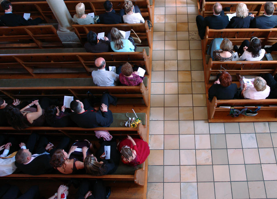 People are seated in pews, viewed from above, in what appears to be a formal setting, possibly a wedding or church service