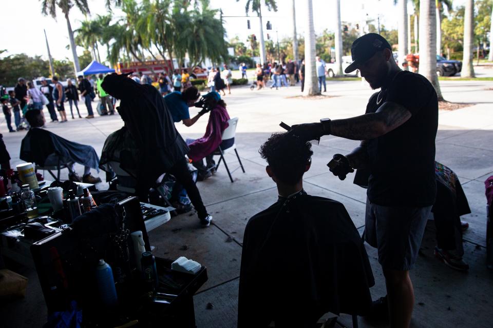 A youth has his hair trimmed by Matt Spinelli, a volunteer barber at the SWFL Hunger and Homeless CoalitionÕs annual "point in time" homeless count at City of Palms Park in Fort Myers on Saturday, Jan. 27, 2024. Vendors were set up at the event to help the homeless which included, food, hygiene kits, clothes and other help.