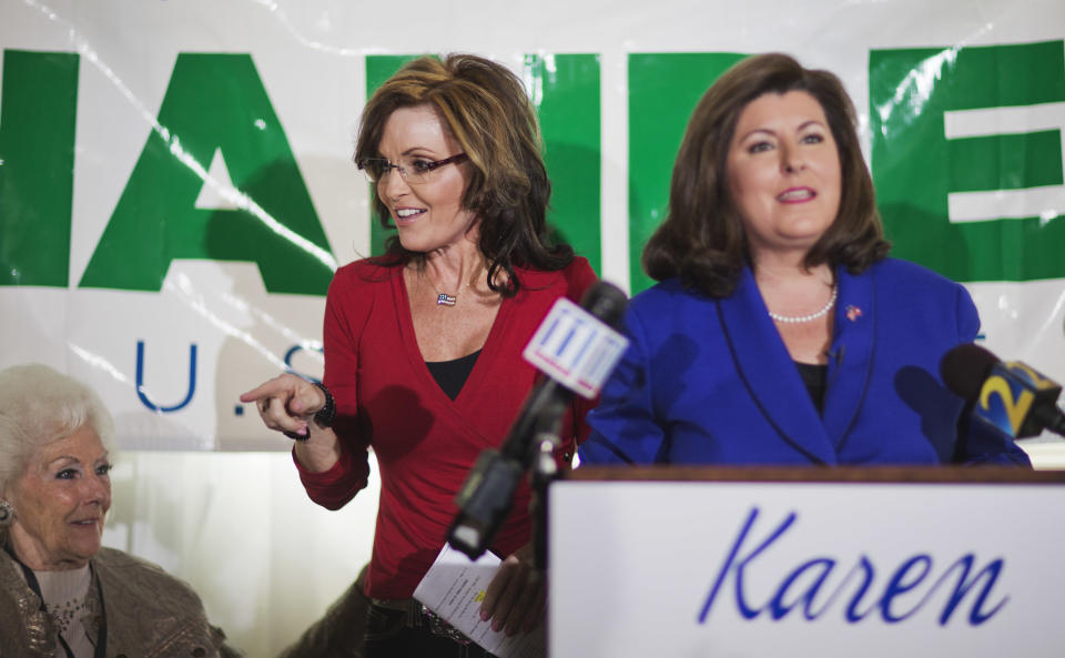 Former Alaska governor and 2008 Republican vice presidential nominee Sarah Palin, left, gestures to the crowd as she surprises a county women's group meeting to campaign for Republican candidate for U.S. Senate Karen Handel, right, Thursday, April 3, 2014, in Union City, Ga. Palin is riding to the defense of the only Republican woman in the nomination fight for Georgia's open Senate seat, hitting back against GOP rival David Perdue's apparent dismissal of Karen Handel's high school education. (AP Photo/David Goldman)