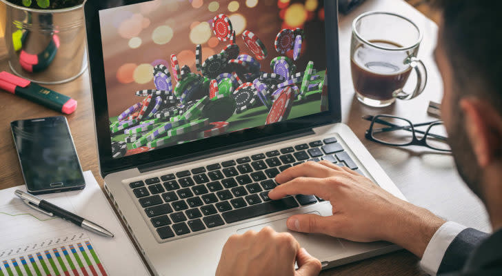 A man looking at a computer with poker chips on the screen.