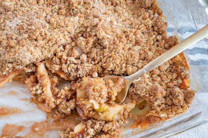 close up of serving spoon in the apple crisp pan with some pioneer woman apple crisp already served