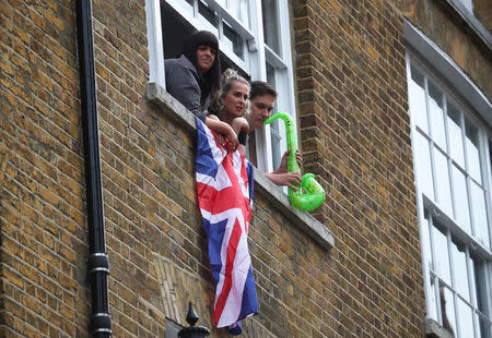 People lean outside of windows as they wait for Britain's Queen Elizabeth to arrive for her visit of a replica of one of the original Sainsbury's stores in London, Britain May 22, 2019. REUTERS/Hannah Mckay