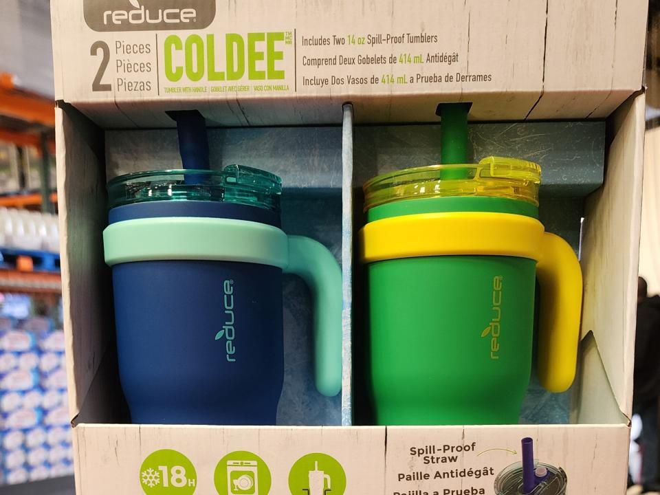 A tan package with "Reduce Coldee" text and a dark-blue and light-blue mug and a green and yellow mug in package