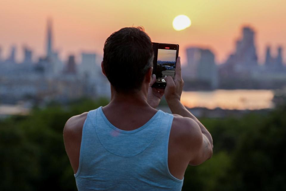 People take pictures of the sunset from Greenwich Park view point (REUTERS)