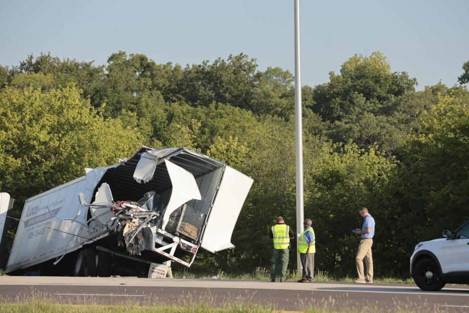 Officials examine a wrecked tractor-trailer that a Greyhound bus collided with on the exit ramp to a rest area on westbound Interstate 70 in Highland, Ill., on Wednesday, July 12, 2023. (Christian Gooden/St. Louis Post-Dispatch via AP)