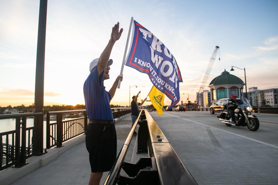 A supporter of former President Donald Trump waves a "Trump won" flag while waving at passing traffic on the Southern Boulevard Bridge in November 2022 in West Palm Beach.