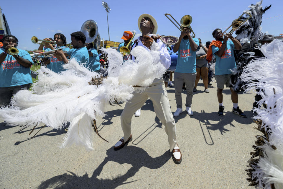 Members of the Zulu Steppers parade with the New Groove Brass Band along the Fair Grounds at the New Orleans Jazz and Heritage Festival in New Orleans, Thursday, April 25, 2024. (AP Photo/Matthew Hinton)