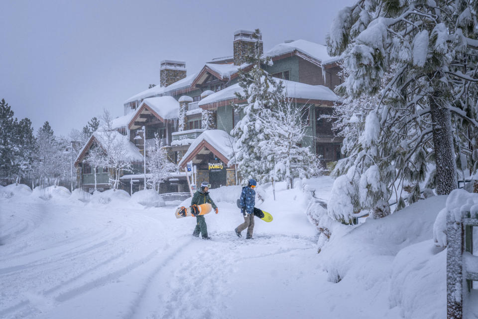 In this photo provided by Mammoth Lakes Tourism, snowboarders walk in the snow on Monday, Feb. 19, 2024, in Mammoth Lakes, Calif. (Jacob Myhre/Mammoth Lakes Tourism via AP)